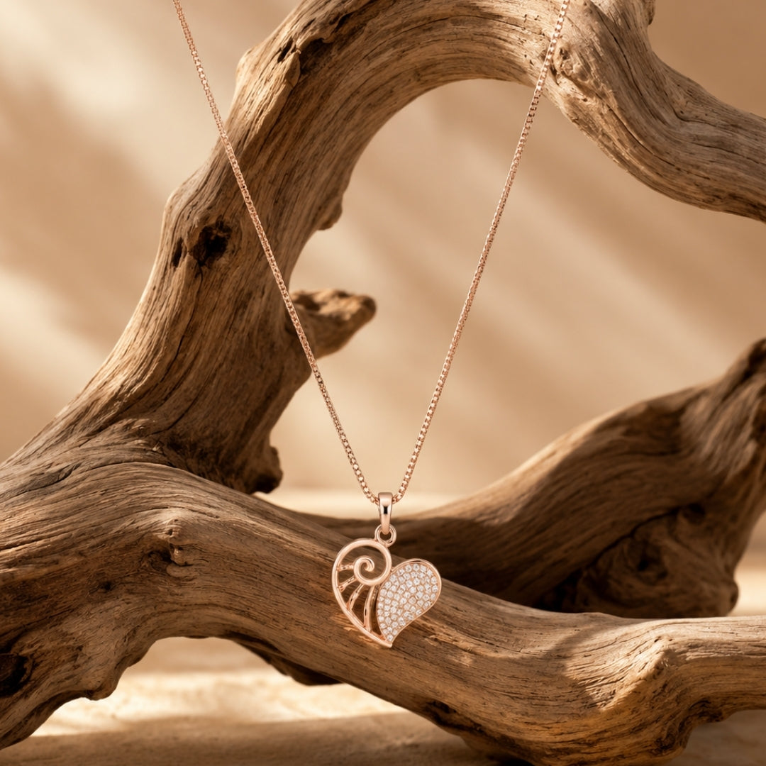 Rose-gold heart pendant necklace with sparkling detail styled on driftwood